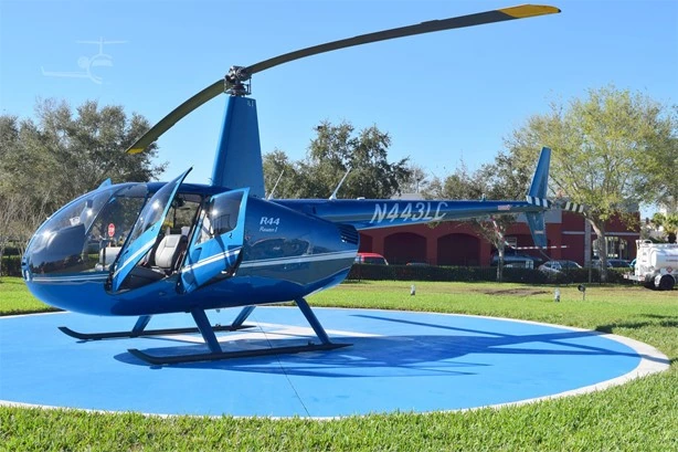 Blue Robinson R44 Raven I helicopter with doors open on a helipad
