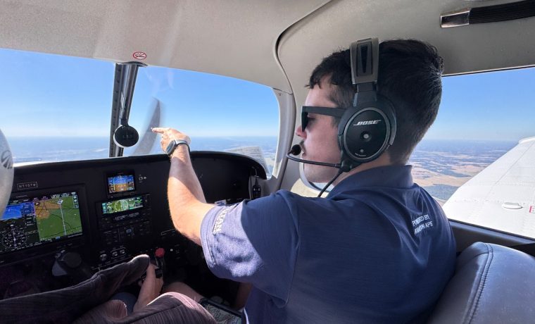 Right Rudder flight instructor wearing a headset and pointing ahead during an in-flight lesson
